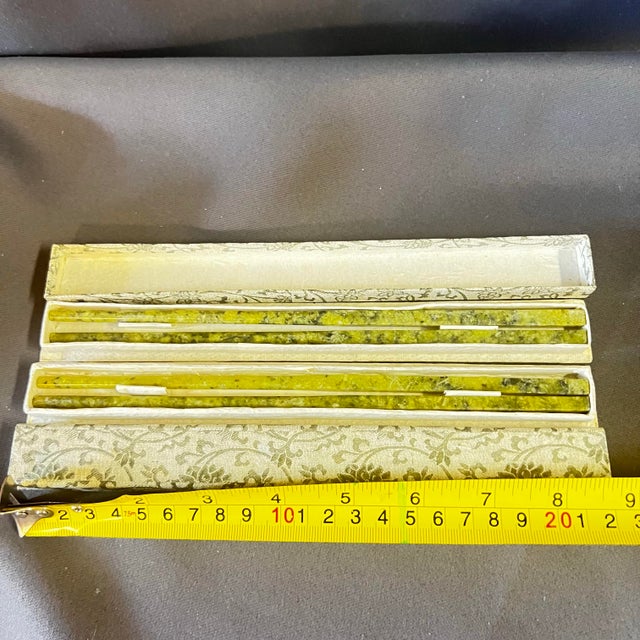 A striking vintage set of Chinese stone chopsticks, hand-carved from richly mottled jade-toned mineral stone in layered...