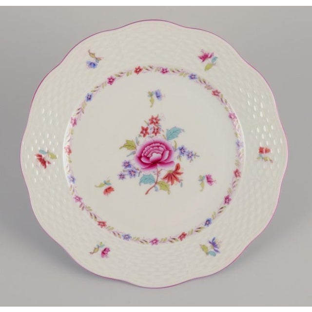 Herend, a set of twelve porcelain plates. Hand-painted with polychrome floral motifs. Pink rim. Marked and dated 1944....