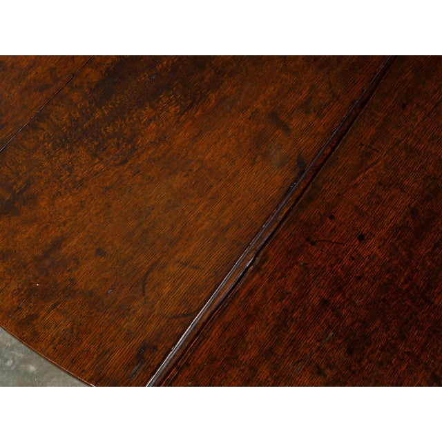 An English rustic drop-leaf gateleg table from the 18th century, with oval top and turned legs. Created in England during...
