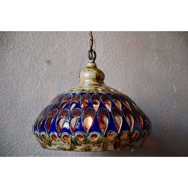 This large pendant light is made of openwork ceramic, partially enameled. Impressive and imposing, it distills a soft...