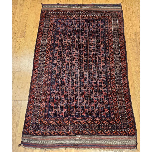 This early 20th century vintage Baluch tribal area rug features an allover geometric design woven in a striking palette of...