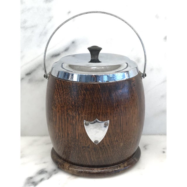 English oak biscuit barrel which retains its original porcelain liner and is decorated with a silverplate crest. DETAILS...