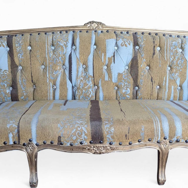 An early 20th-century French-style sofa with a carved dark wood frame and custom striped upholstery in soft blue, cream,...