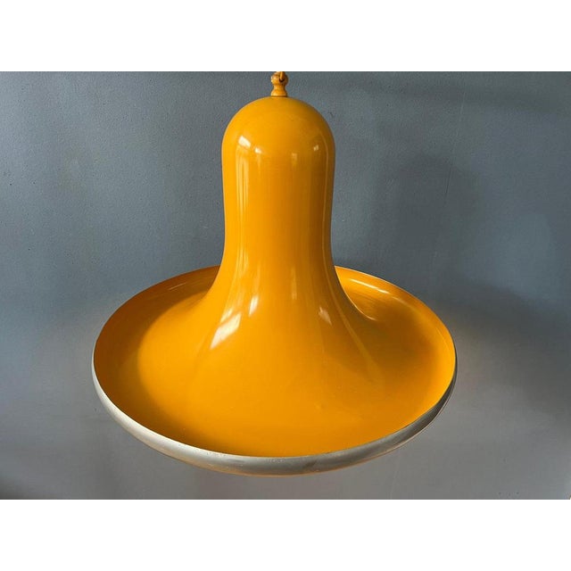 Rare yellow mid century space age pendant lamp in ufo or hat shape. The lamp is made out of metal and has a glossy yellow...