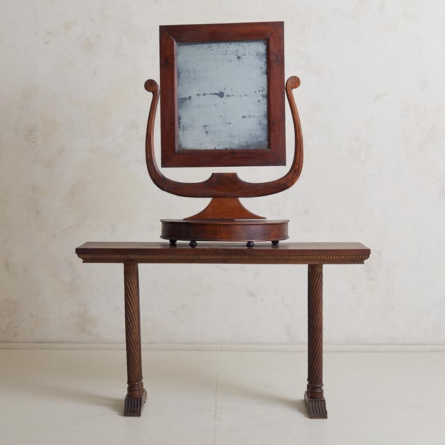 A handsome antique vanity mirror with a harp walnut frame and a demilune pedestal base. The frame supports a rectangular...