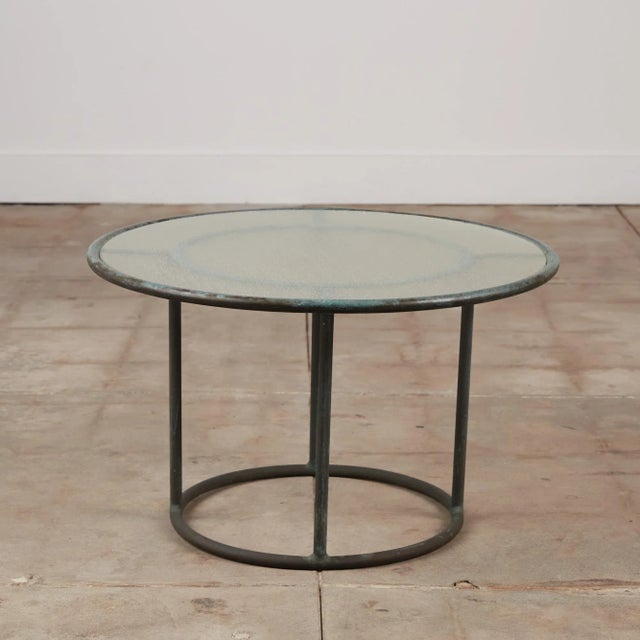A side table in patinated bronze designed by Walter Lamb and produced by Brown Jordan. The round table is supported by...