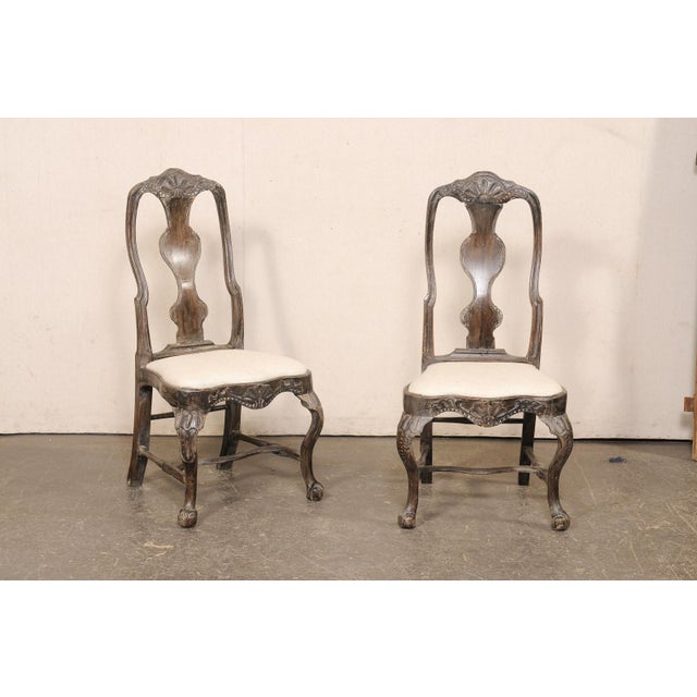 A Swedish pair of period Rococo side chairs, with upholstered seats, from the 18th century. These antique chairs from...