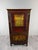An elegant display cabinet in stained wood, richly decorated with gilt trim and delicate floral motifs. the upper section...