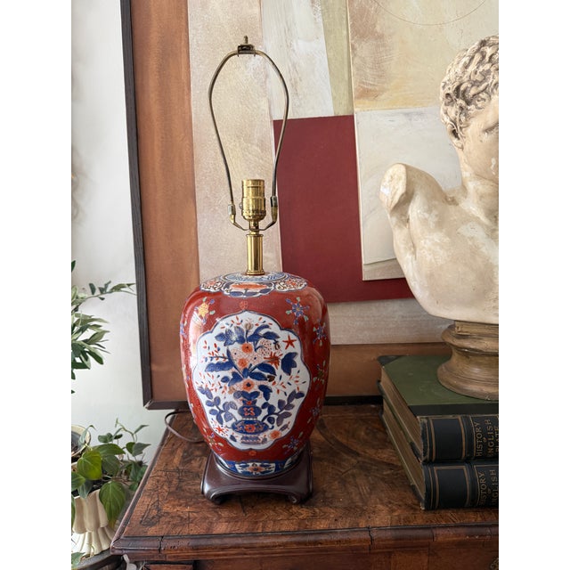 A richly detailed vintage chinoiserie table lamp featuring an Imari-inspired palette of deep burgundy, navy blue, dark...