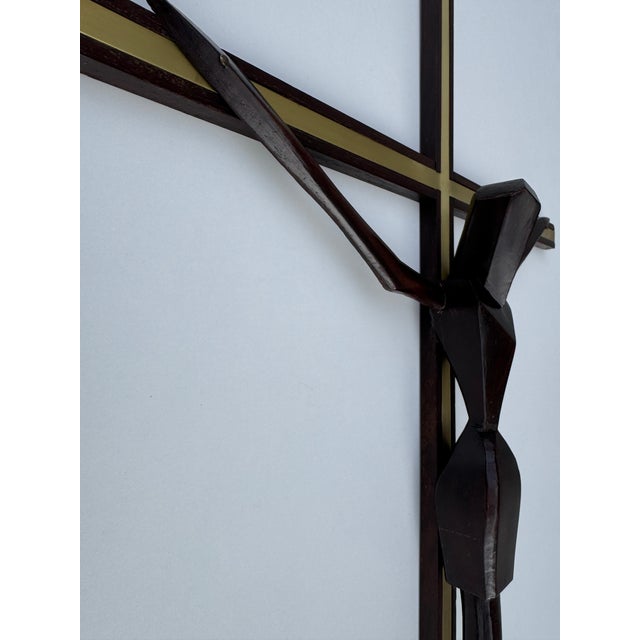 A sculptural Mid-Century Modern crucifix handcrafted from solid dark-stained wood with refined brass inlay details. The...