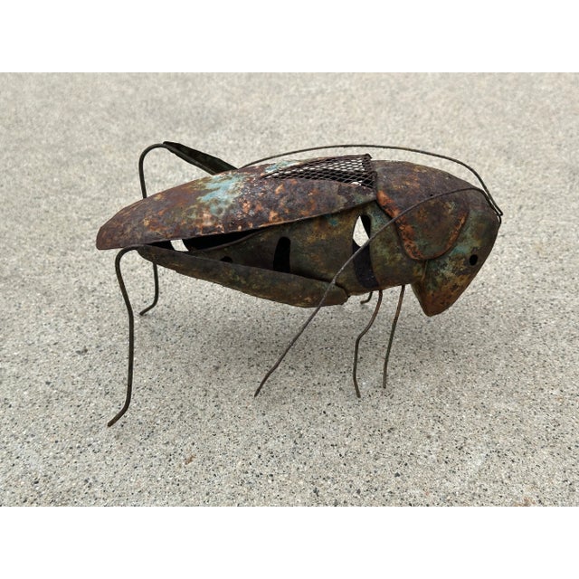 A whimsical handcrafted metal grasshopper candle holder with rich natural patina and sculptural character. Made from...