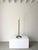 A vintage metal candlestick holder, blacksmith made in the form of a chain. The chain links coil around on the floor to...