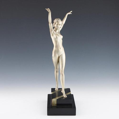 An art deco patinated bronze sculpture of a nude woman with arms outstretched in a striding pose. Set over a marble and...