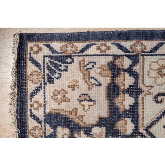 A 9' x 12' hand-knotted wool rug with a bold Heriz-style geometric medallion in navy and ivory on a charcoal gray ground....