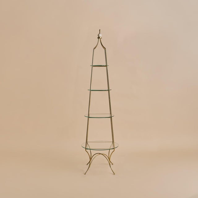 A mid-20th century French four-tier étagère crafted in warm brass. The open framework rises with a gentle taper, its...