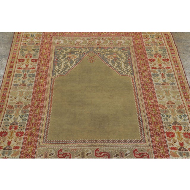 Hand-knotted in wool, this 4x6 Vintage Turkish Anatolian Prayer Rug, circa 1950–1959, features a serene olive mihrab...