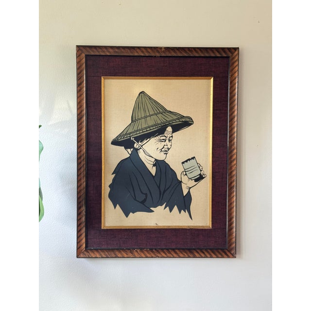 Pair of vintage framed textile artworks depicting expressive Asian figures engaged in traditional crafts. Lightweight.