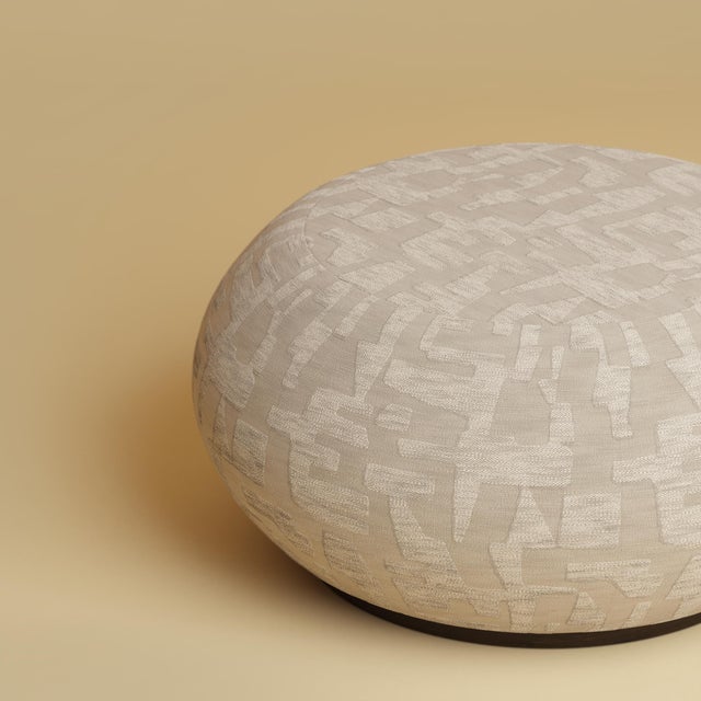 The Kuna is an upholstered oak pouf, Dedar Ur drawn over a frame of solid smoked oak. It brings textile and give to a...