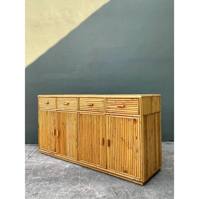This vintage stacked rattan credenza is entirely clad in densely arranged bundles of natural rattan poles, their vertical...