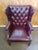 This burgandy armchair is crafted with tufted leather upholstery and brass tacks. It is set on a dark stained wooden...