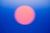 This photographic work presents a softly blurred orb in shades of pink against a gradient of deep blue, evoking a serene...