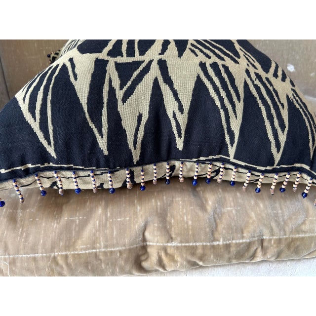 A pillow made from a woven cotton textile with abstract pattern, embellished with vintage beaded fringe