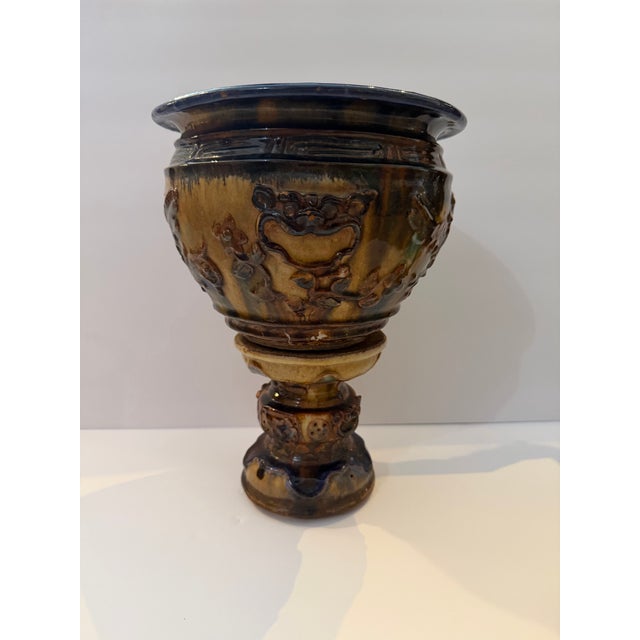 Dramatic vintage ceramic jardinière planter featuring ornate figural and scrolling relief decoration with a richly layered...
