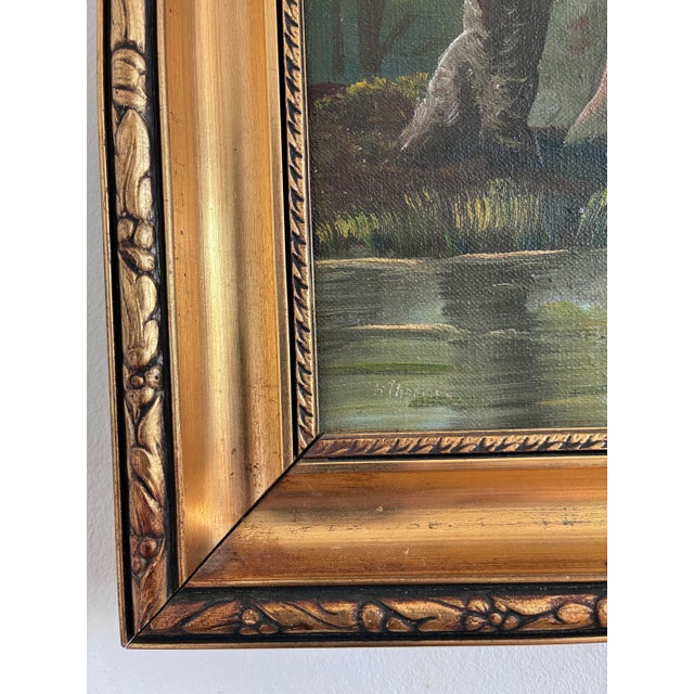 This original vintage oil painting from the 1940s shows a forest landscape with tall trees, water, and a blue sky. The...