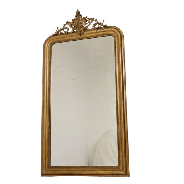 Antique Louis Philippe floor mirror made of gold-painted pine, featuring a charming floral cartouche at the top and a...