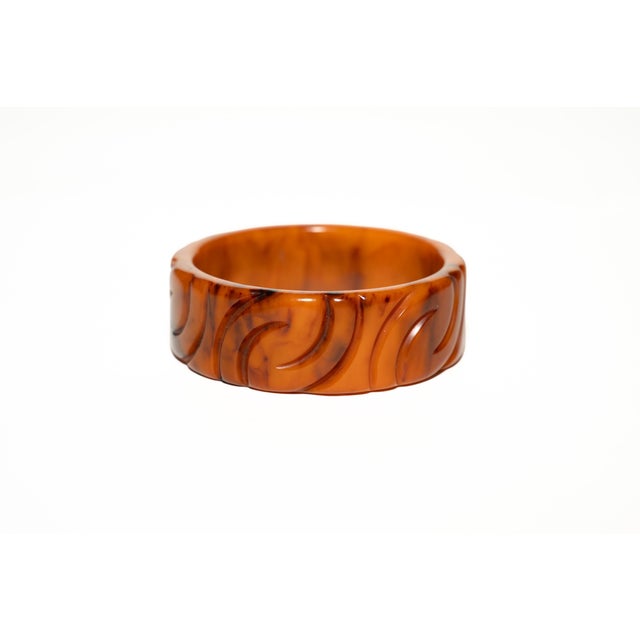 This vintage Art Deco carved bakelite bangle carved bracelet has beautiful tonal ranges of colors of orange amber, caramel...