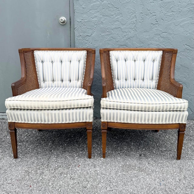 Elegant pair of vintage Hollywood Regency barrel chairs featuring warm wood frames, gracefully curved silhouettes, and...