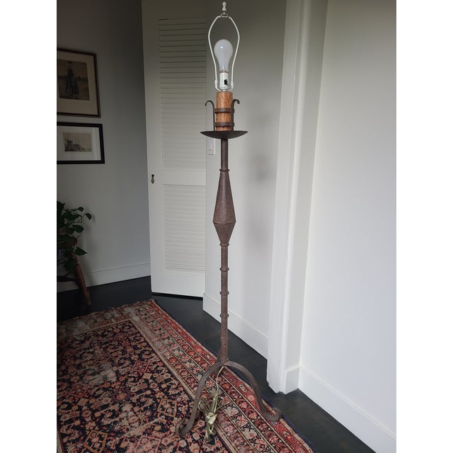 Stunning 1970's sculptural floor lamp crafted from iron. Features a slender candlestick stem over a tripod base. The lamp...