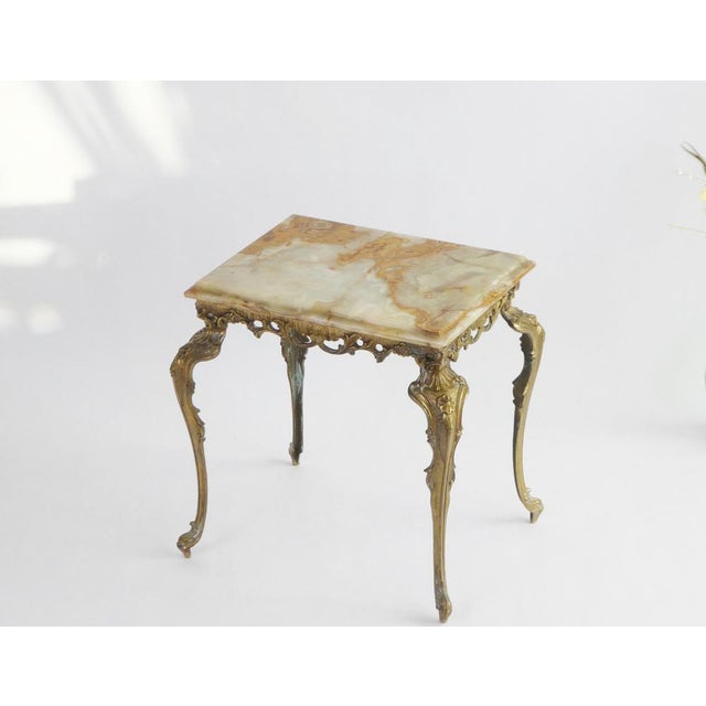 Small rectangular onyx table with an ornate brass base. The table is made in Italy and typical from the Hollywood Regency...