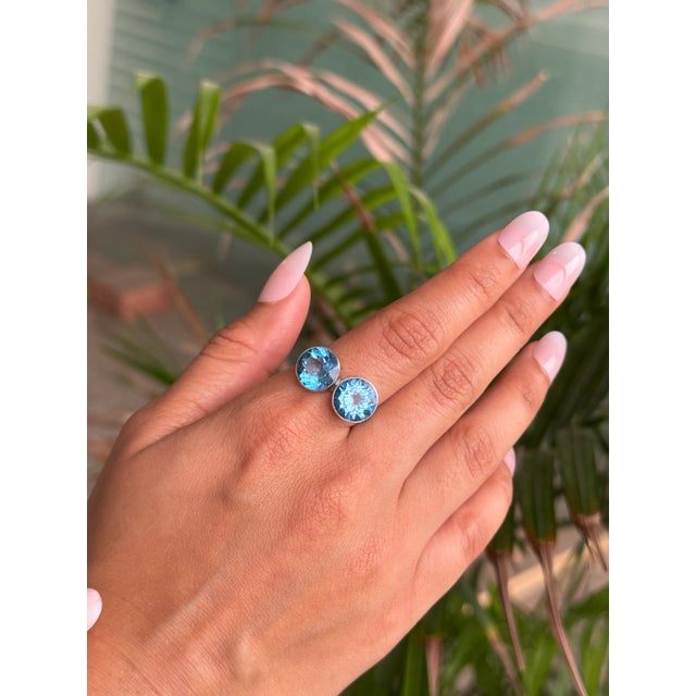 This elegant sterling silver ring highlights the beauty of two brilliant round blue topaz gemstones, weighing a total of...