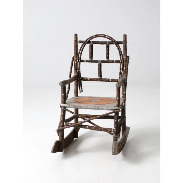 An antique Adirondack children’s rocking chair showcasing rustic folk art charm. Crafted from bentwood twigs, it features...