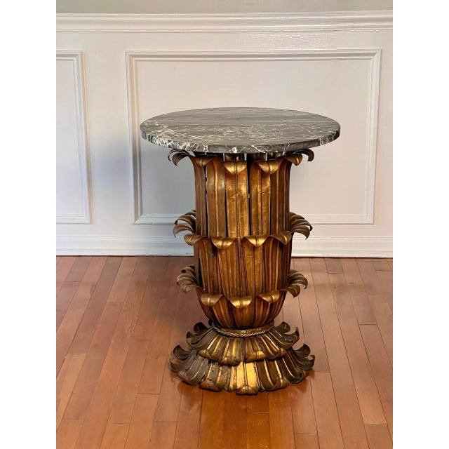 Hollywood Regency gilt metal plume leaf side table with a round marble top, Italy, 1960s. A striking table featuring a...