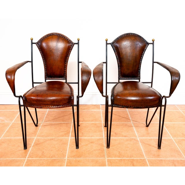 A fantastic and rare pair of mid century leather, wrought iron and brass armchairs in lovely vintage condition. Designed...