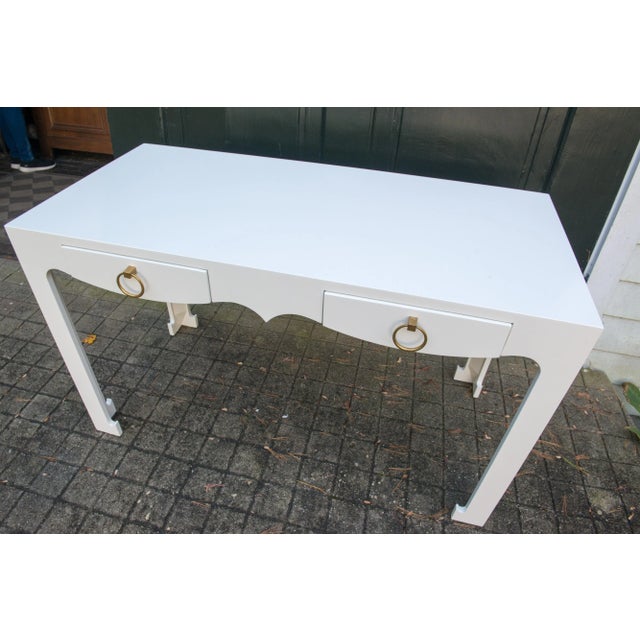 White lacquered desk, two drawers with brass ring pulls. Clearance height 23.5. Desk or console finished on all sides.