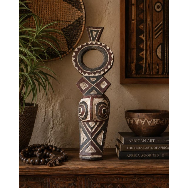 A striking hand-carved African tribal mask sculpture crafted from a single block of wood and finished with traditional...