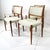 A set of four sculptural teakwood framed dining chairs with woven oatmeal toned fabric back and bottom cushions. An...