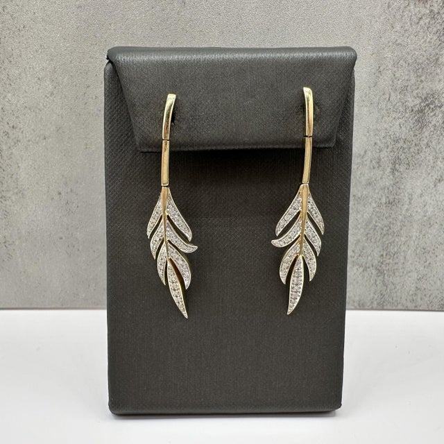 These elegant diamond dangle earrings are crafted in 14kt yellow gold with white rhodium plating on the prongs to enhance...