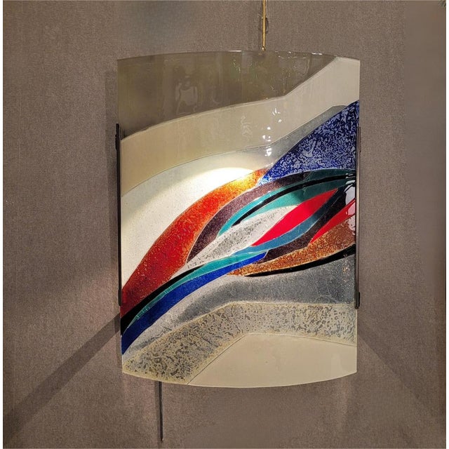 Surprising wall sconce in blown and polychrome glass, whose asymmetrical design is characterized by the wavy lines that...