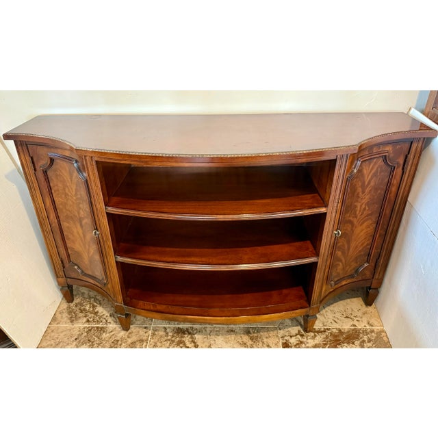 • Bow front Henredon sideboard with flame mahogany veneer and Federal style details. • Features paneled doors, fluted...