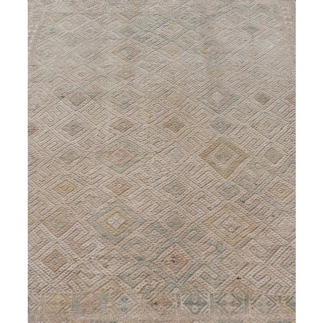 Measures: 5'0 x 6'5 This vintage Turkish Kilim features soft neutral colors and a woven texture. The design is a sub-...
