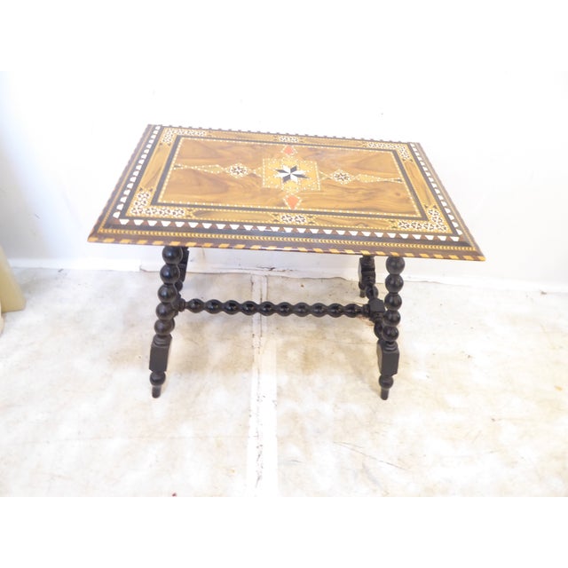 This table with top inlaid with various woods and bone, has ebonized finished turned legs and is 19.75"H x 24"L x 16"D.