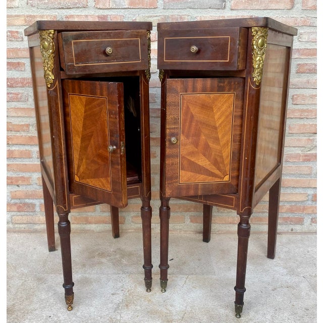 Elegant pair of French bedside nightstands in the Empire style, crafted in wood and decorated with contrasting geometric...