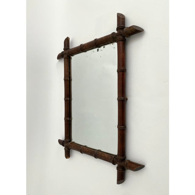 This French faux bamboo mirror with a darker brown finish to the frame and likely the original mirror with minor spots of...