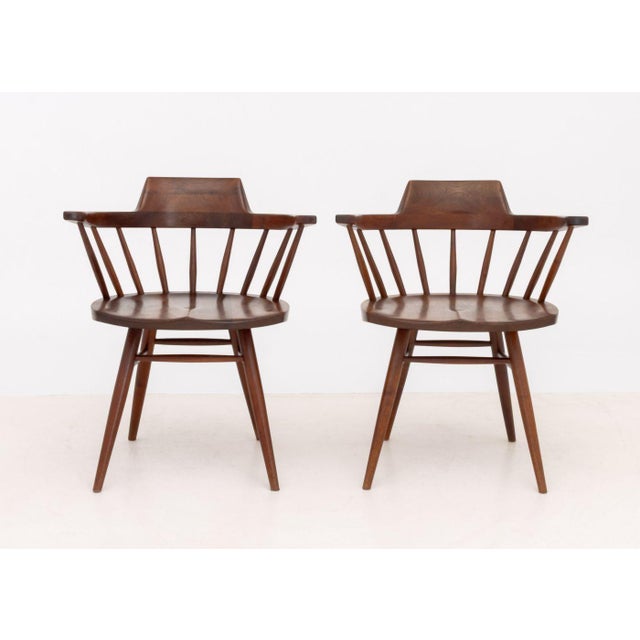 Pair of George Nakashima (American, 1905-1990) American Walnut Captain's Armchairs, 1962, with spindle backs on turned...