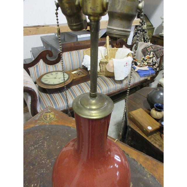 Chinese porcelain bottle vase in a glossy oxblood red glaze, mounted as a table lamp on a carved and pierced giltwood...