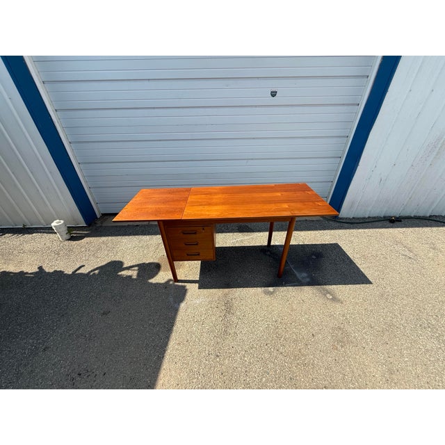 Offered is a Mid-Century Modern Teak Drop Leaf Desk featuring clean Danish modern lines, tapered round legs, and three...